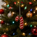 Detail einer rot-weißen Zuckerstangen-Deko mit Stechpalme an einem festlichen Weihnachtsbaum - Zuckerstange