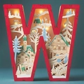 Macro shot of wooden letter W light with laser-cut snowy cabin and reindeer scene - Letter W