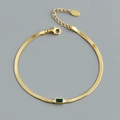 Detail eines goldenen Schlangenkette-Armbands mit einem rechteckigen grünen Zirkon - Gold