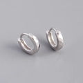 Macro shot of S925 sterling silver huggie earrings with a faceted diamond-cut texture - 925 Silver / White Gold
