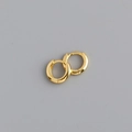 Primer plano de aretes huggie dorados con acabado pulido liso sobre un fondo gris - 10mm / Dorado