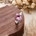 Three-stone ring with heart-shaped pink zircon and silver band on a wooden display - Heart Style / Pink