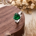 Silver ring with large green heart-cut gemstone and white side stones on wood base - Heart Style / Green