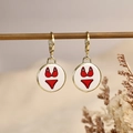 Golden hoop earrings with white round pendants featuring a red bikini design and dry floral accents - Bikini Style