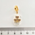 Detailansicht eines Kleeblatt-Perlenanhängers mit Goldbeschichtung und Zirkonia neben Lineal - Dreiblattblume
