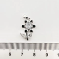 Détail d'un pendentif floral avec zircons blancs et finition argentée à côté d'une règle - Tournesol / Or blanc
