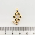 Vue détaillée d'un pendentif fleur plaqué or avec zircon à côté d'une règle métrique - Tournesol / Or 18K