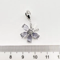 Vue détaillée d'un pendentif papillon doré avec pierres violettes et zircone près d'une règle - Marguerite en Zircon Violet Or Blanc