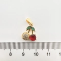 Vue macro d'un pendentif cerise plaqué or avec des cristaux de zircone rouges et verts - Cerise / Or 18K