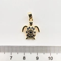 Vue détaillée d'un pendentif tortue doré avec pierres bleues à côté d'une règle graduée - Tortue de mer / Or 18K