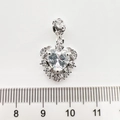 Gros plan sur pendentif cœur argenté avec zircone et roses 3D sur fond blanc brillant - Cœur d'argent
