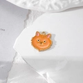 Détail d'une breloque chat orange émaillée avec bordure dorée sur un socle en pierre blanche - Chat Orange avec Trois Poils