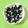 Gros plan de pendentifs billard n°8 en résine noire dans un plat en céramique - Style Boule de Billard Noir
