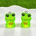 Macro shot of two green resin frog charms with golden ingots in a white ceramic tray - Gold Ingot Frog