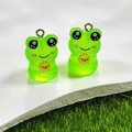 Close-up of cute glow-in-the-dark resin frog pendants with metal rings for DIY jewelry - Sun Frog
