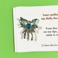 Detailed macro view of a silver butterfly pendant with blue gemstone and resin wings - Blue