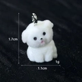 Vista macro di un ciondolo cucciolo floccato bianco con dimensioni e anello - Mini Cane