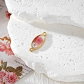 Macro view of gold oval resin charm with real pink dried flowers and double loops - Oval Pink Flower