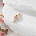 Macro detail of eye-shaped resin charm with pink dried flowers and golden frame - Eye-shaped Pink Flower