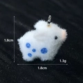 Macro di un ciondolo a forma di coniglio floccato bianco con puntini blu, 1,8cm e 1,3g - Piccolo Maialino di Fiori