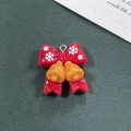 Dettaglio macro del ciondolo natalizio in resina rossa con campanelli d'oro e fiocchi - Stile Campana Rossa
