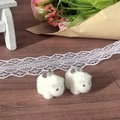 Close-up of white flocked rabbit pendants with silver rings for DIY jewelry making - White Horse