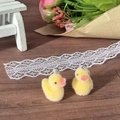 Macro shot of cute flocked yellow duck charms with silver metal rings on a wooden desk - Little Duck