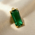 Macro shot of an emerald-cut green crystal pendant with a gold-plated metal prong setting - Green