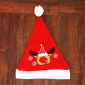Cappello di Natale rosso con ricamo di renna e fiocchi di neve su sfondo in legno scuro - Cervo di Natale Stile
