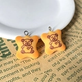 Detail of yellow resin bear biscuit charms with silver ring on newspaper background - Bear Food