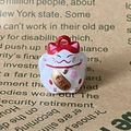 Close-up of ceramic lucky cat bell pendant with cherry blossom pattern and gold coin - Red