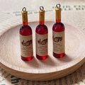 Close-up of miniature resin red wine bottle charms with detailed vintage labels for DIY craft - Gold Wine Bottle (F512)