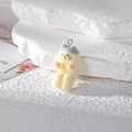 Vue macro d'un pendentif chat floqué jaune et gris avec boucle argentée sur pierre - Chat se Chauffant les Mains
