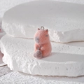 Detailed close-up of a pink flocked capybara pendant on a textured white stone surface - Knocking Wooden Fish Style