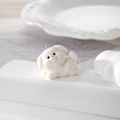 Close-up of a white flocked puppy pendant on a geometric stand for DIY jewelry making - White Dog