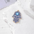 Dettaglio pendente Mano di Fatima dorata con malocchio blu su sfondo in pietra - Oro Blu Gocciolamento d'Olio (F)