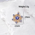 Vista macro di ciondolo esagonale dorato con occhio blu e cristalli, 2,9cm x 2,3cm - Fiocco di Neve Esagonale Oro (G_AN18)
