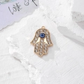 Macro del ciondolo a mano di fatima dorato con cristalli e dettaglio dell'occhio blu - Oro Pavé Strass (C)
