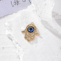 Dettaglio macro del ciondolo Mano di Fatima dorato con occhio turco blu e strass lucidi - Oro Cavo Strass Palmo (S)
