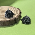 Detailed close-up of cute resin hedgehog pendants with white spikes on wooden slice - Black Hedgehog