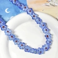 Blaue Glasblumen-Halskette auf weißem Teller mit Mondmuster-Hintergrund im 45-Grad-Winkel - Königsblaues Blumenmuster
