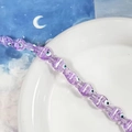 Dettaglio di perline viola a forma di pesce con occhio di Allah su piatto bianco - Stile pesce malocchio viola (N)