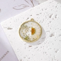 Close-up of handmade resin daisy pendant with gold alloy edge and pearl detail for DIY - White