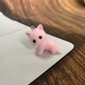 Vue macro d'une petite breloque chat rose floquée avec texture douce et boucle en métal - Rose