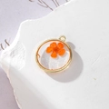 Dettaglio pendente tondo dorato con fiore essiccato arancione e glitter in resina - 4 GH55