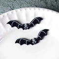 Close-up of black glittery bat charms with white skull pattern for DIY jewelry making - Skull Bat