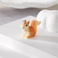Detail view of a fuzzy orange squirrel charm with a metal ring on a minimalist pedestal - Squirrel