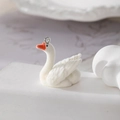 Detailed view of a white flocked swan charm with an orange beak and a metal loop - Swan