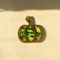 Macro view of pumpkin-shaped wooden charm filled with shiny green star sequins - Green Star Pumpkin