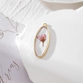 Close-up of handmade oval gold frame pendant with real pink dried flower in clear resin - Small Pink Flower Style (GH26)